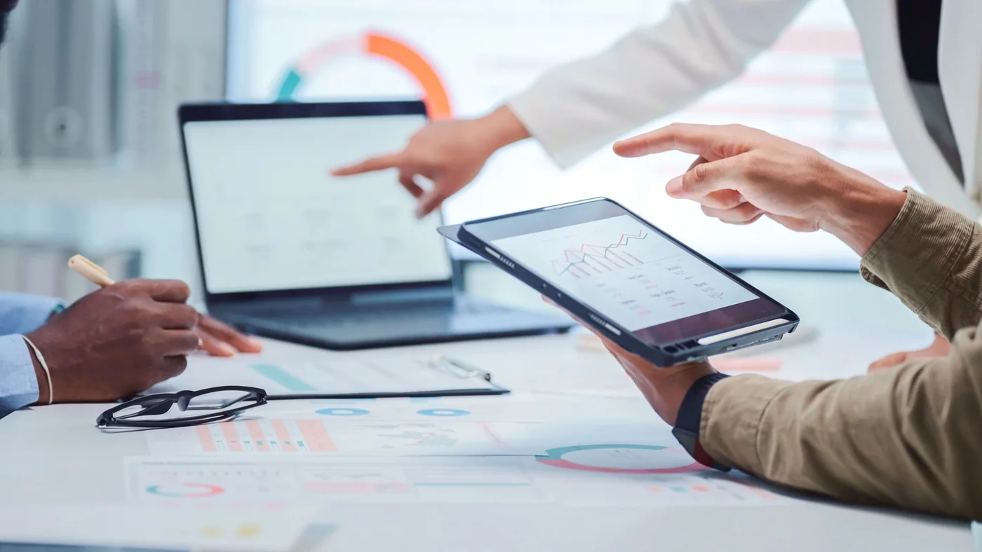 Two executives reviewing performance dashboards on a laptop and tablet